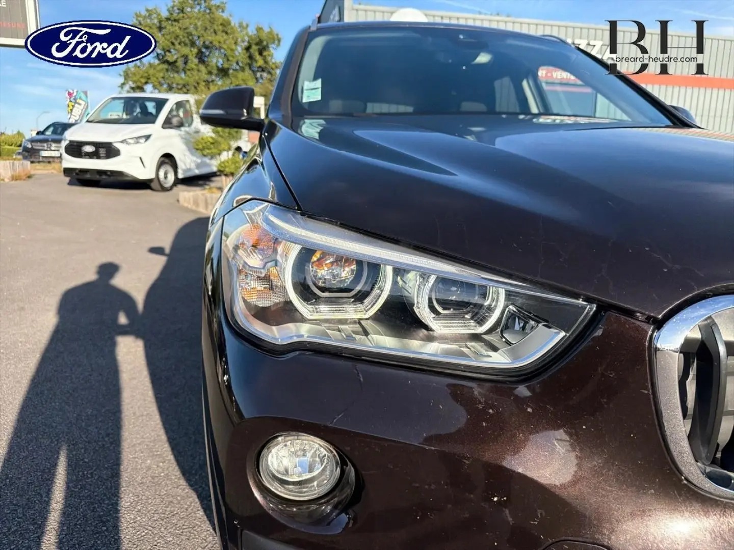 Gros plan sur l'avant gauche d'une BMW X1 sDrive18dA 2018 en Saphirschwarz, mettant en valeur le phare et la calandre.