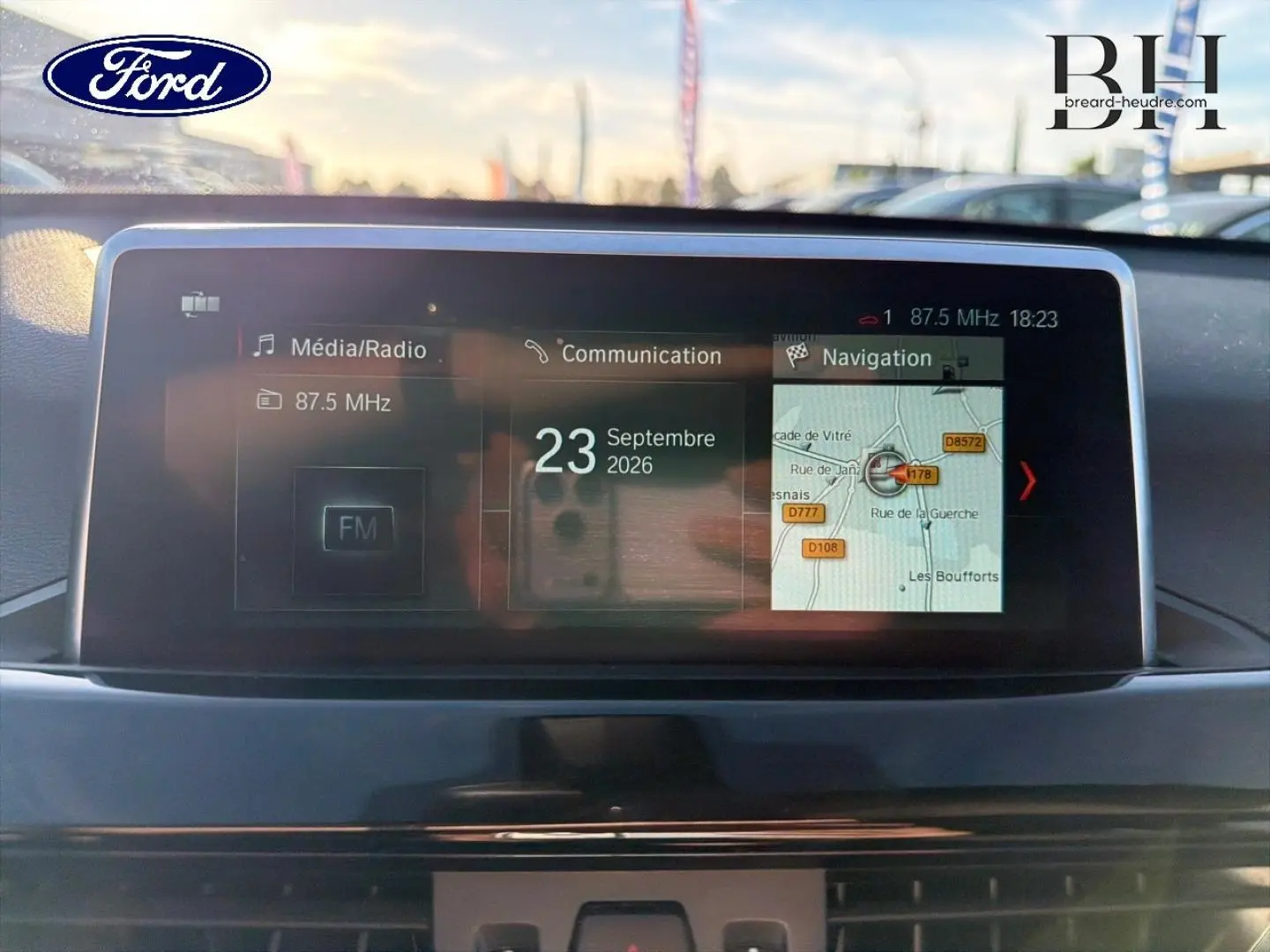 Écran multimédia central d'une BMW X1 sDrive18dA 2018, affichant radio FM et navigation, vue intérieure frontale.