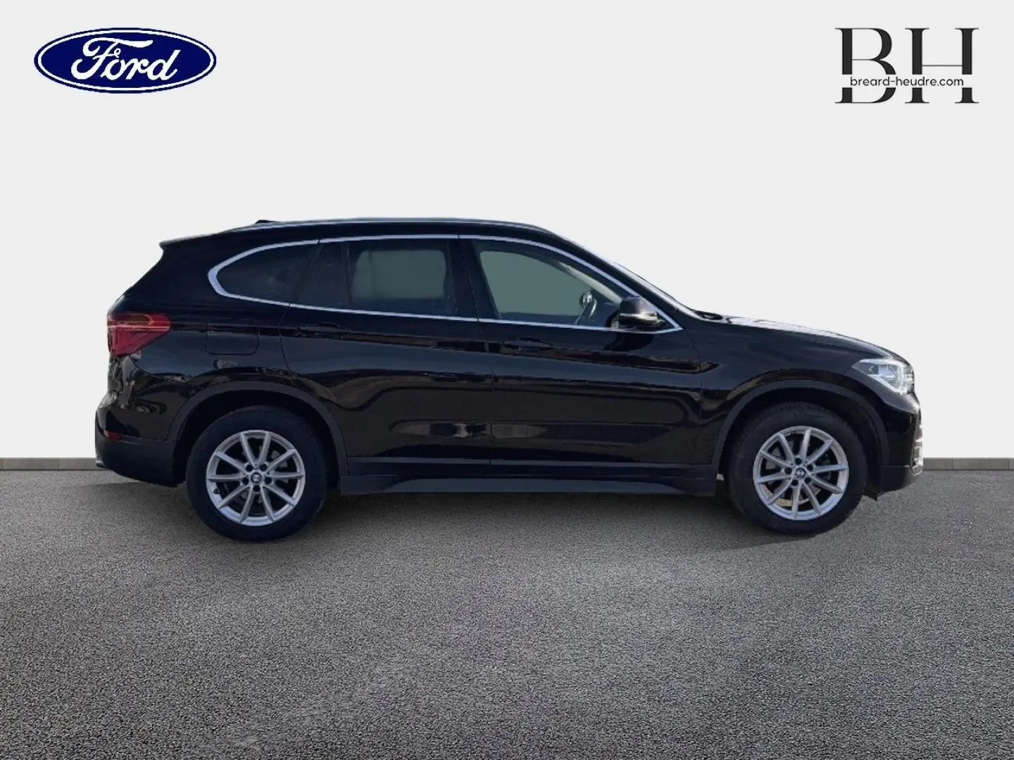 Profil droit d'un BMW X1 sDrive18dA 2018 noir saphir avec jantes alliage et barres de toit visibles.