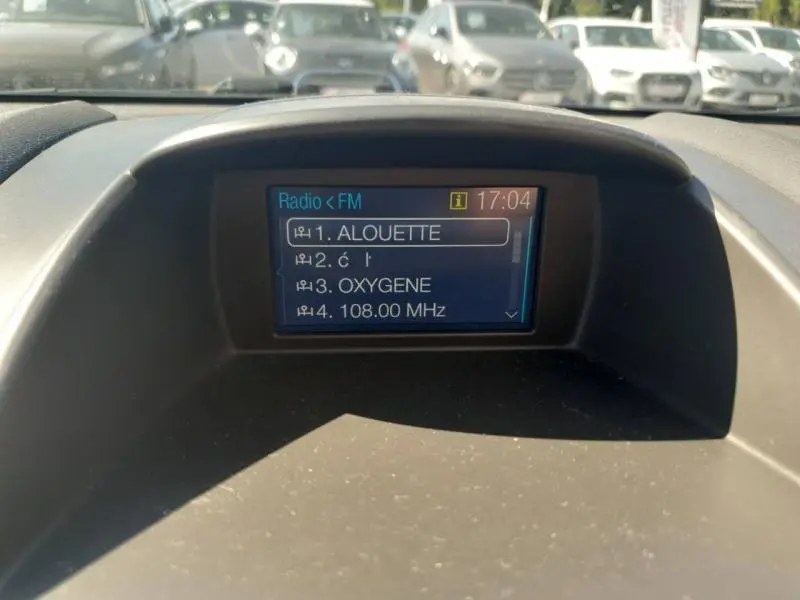 Écran multifonction affichant les stations radio FM dans l'habitacle d'une Ford Fiesta noire, vue de face