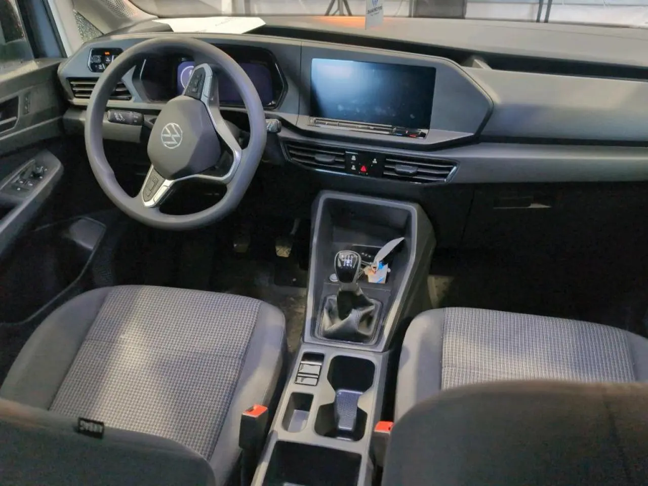 Vue intérieure avant du Volkswagen Caddy Maxi 2024, volant multifonction, tableau de bord digital et boîte manuelle.