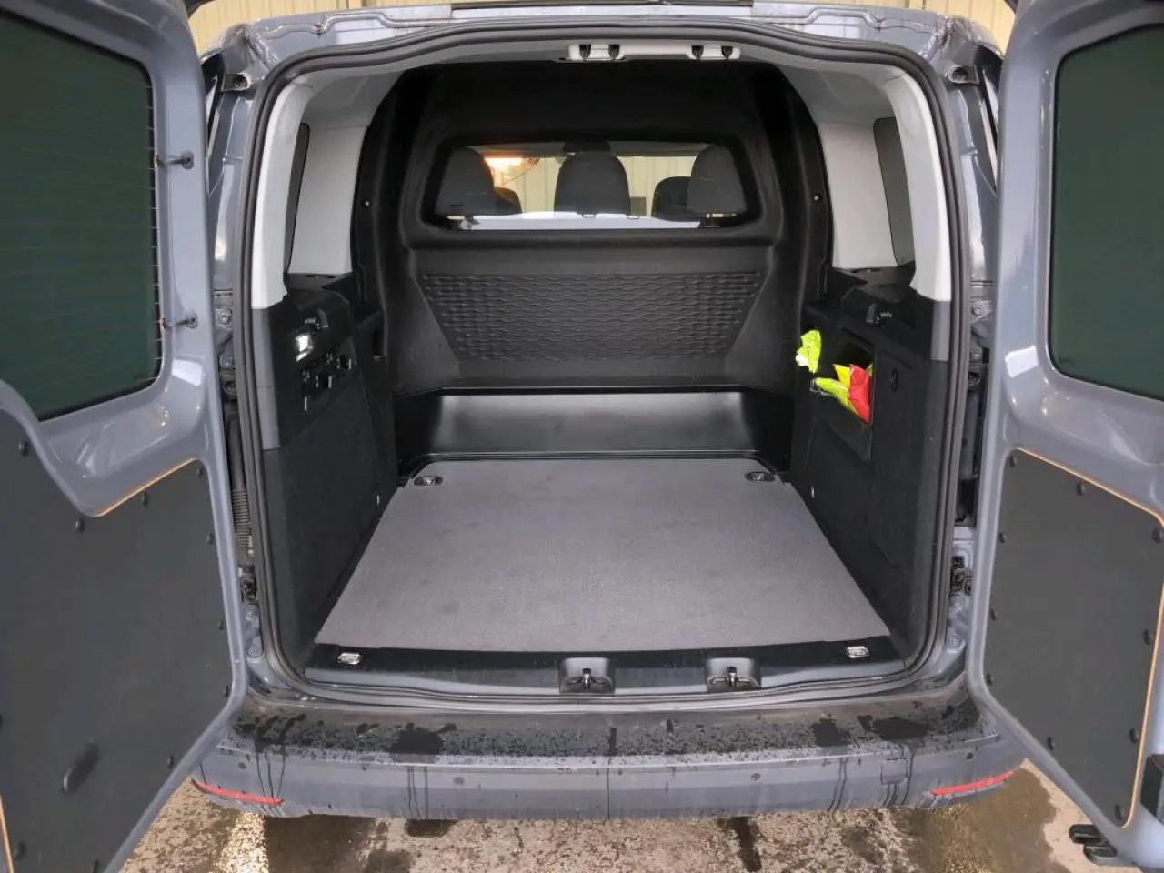 Vue arrière ouverte du Volkswagen Caddy Maxi gris Pure Grey montrant l'espace de chargement vide et les portes battantes.