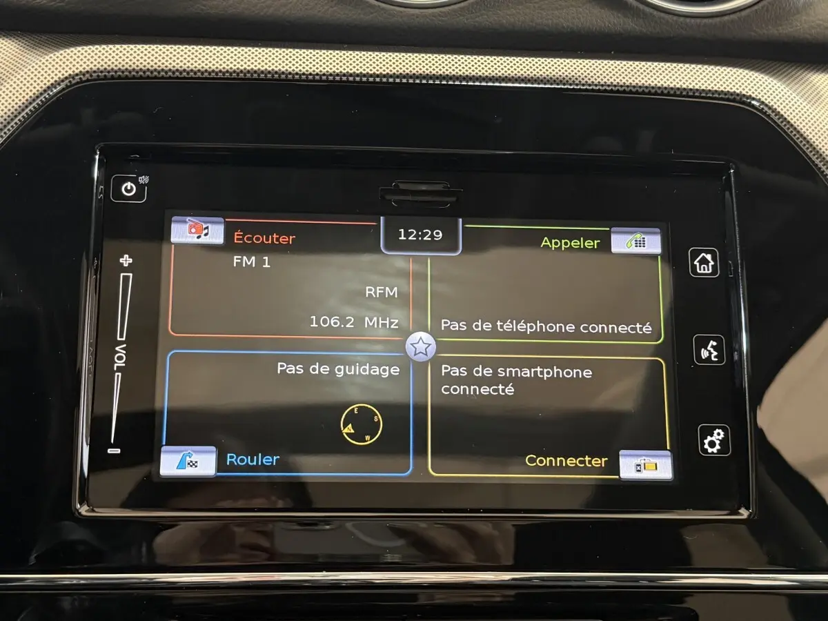 Écran tactile central du tableau de bord du Suzuki Vitara noir, affichant radio et options de connexion.