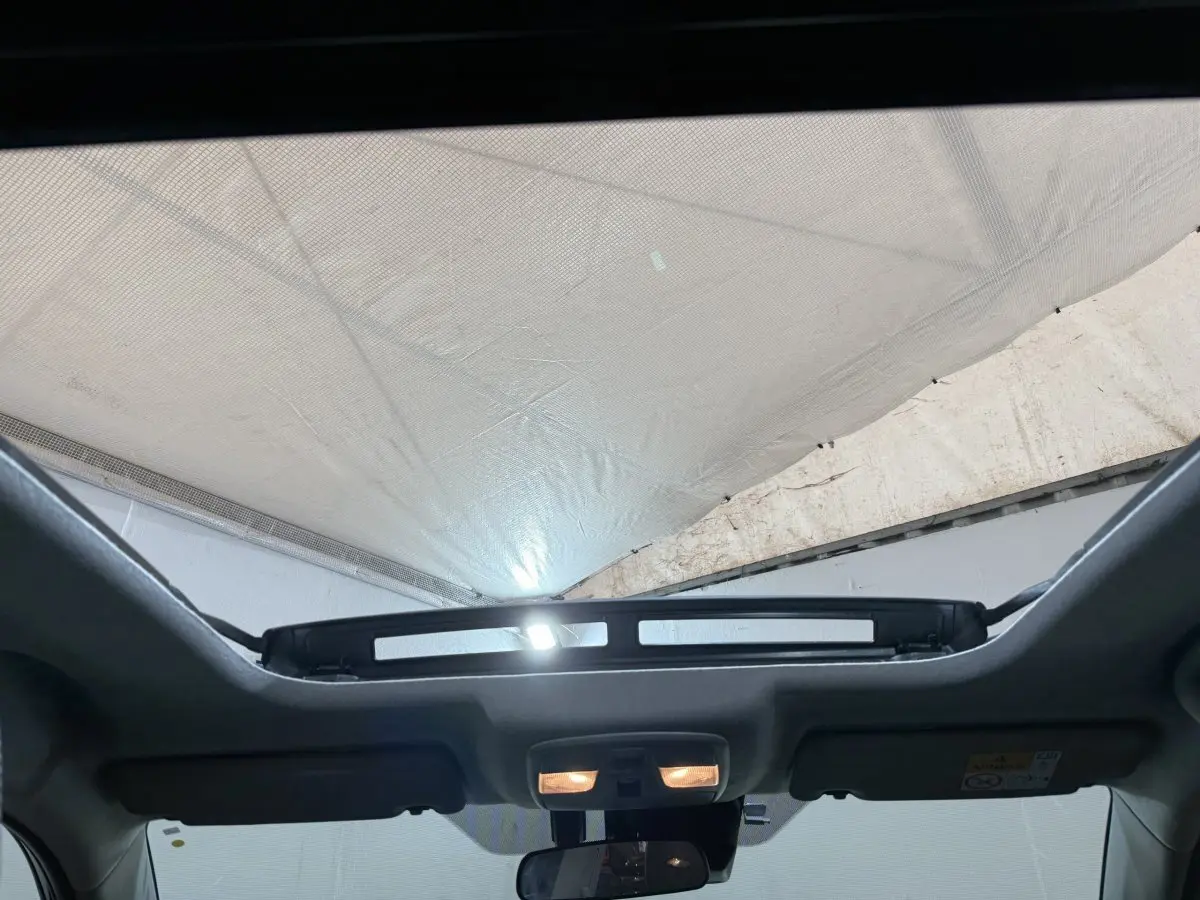 Vue intérieure du toit ouvrant électrique en verre du Suzuki Vitara noir 2022, avec éclairage intérieur allumé.