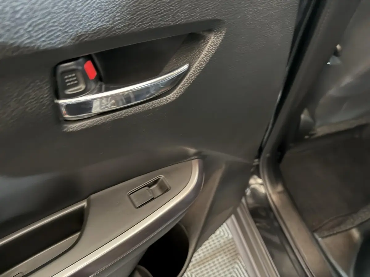 Vue rapprochée de la porte arrière droite noire du Suzuki Vitara 1.5 Dualjet hybrid STYLE avec poignée chromée et commande de vitre.