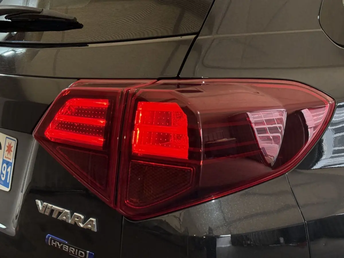 Gros plan sur le feu arrière droit d’un Suzuki Vitara noir hybride avec logo VITARA et HYBRID visible.