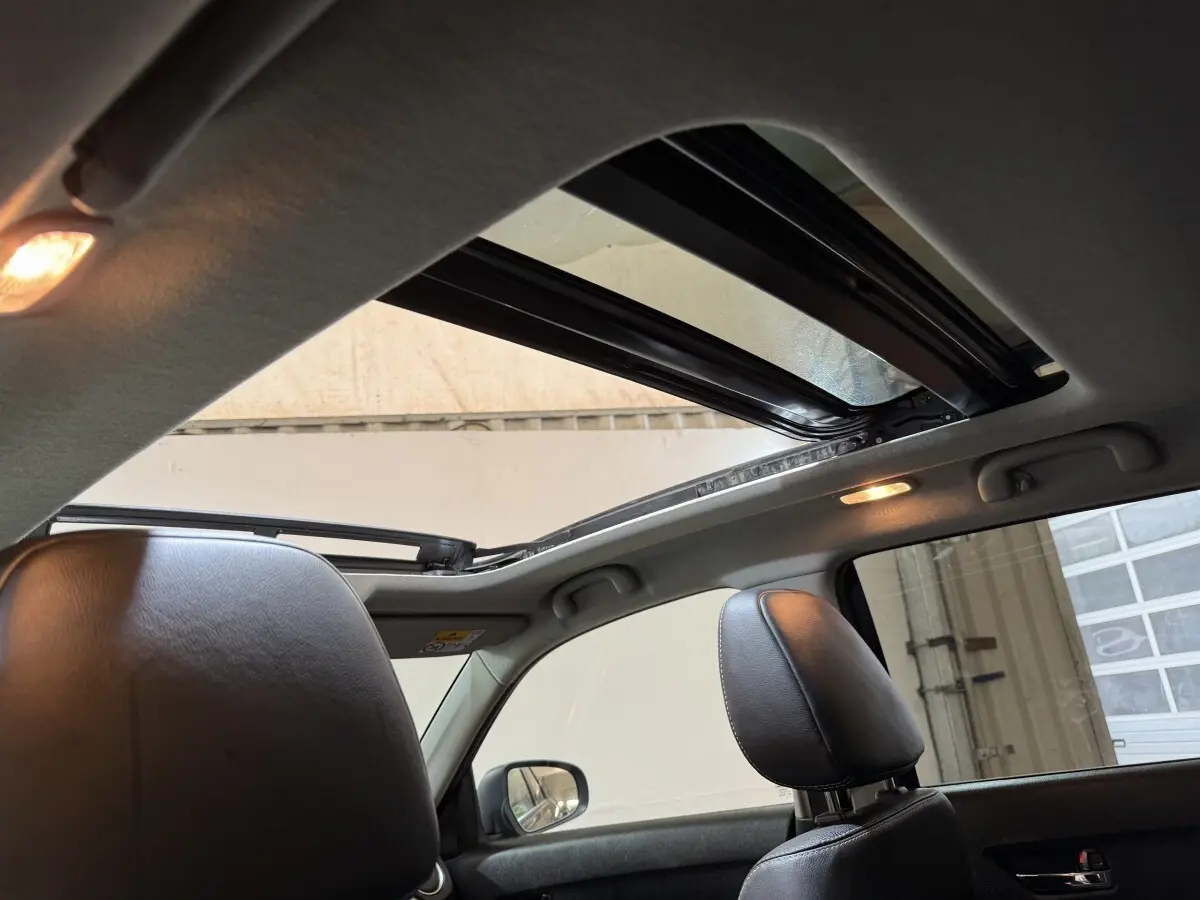 Vue intérieure du toit ouvrant panoramique électrique du Suzuki Vitara noir, avec appuis-tête en cuir visibles côté droit.