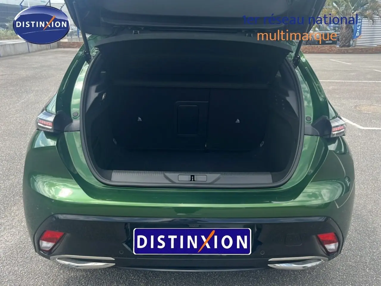 Vue arrière ouverte de la Peugeot 308 2024 vert olivine métal, coffre spacieux et feux arrière modernes visibles.