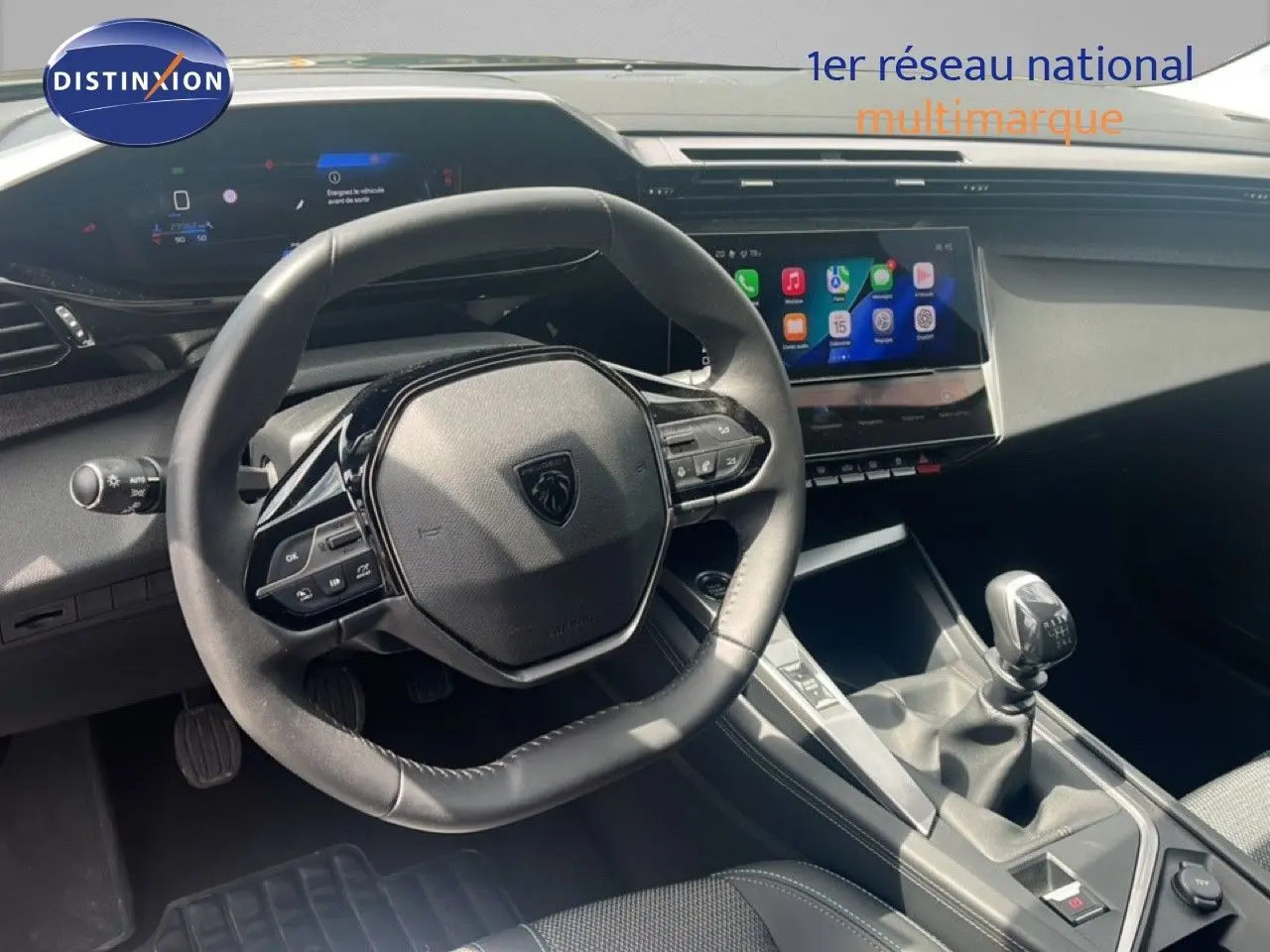 Intérieur de Peugeot 308 2024, vue du poste de conduite avec volant compact et levier de vitesses manuel, ambiance gris noir.