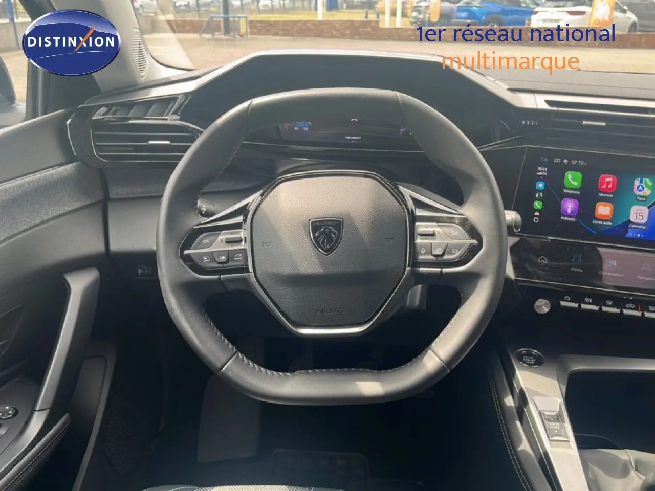 Vue intérieure centrée sur le volant cuir noir de la Peugeot 308 2024 avec écran tactile et tableau de bord digital.