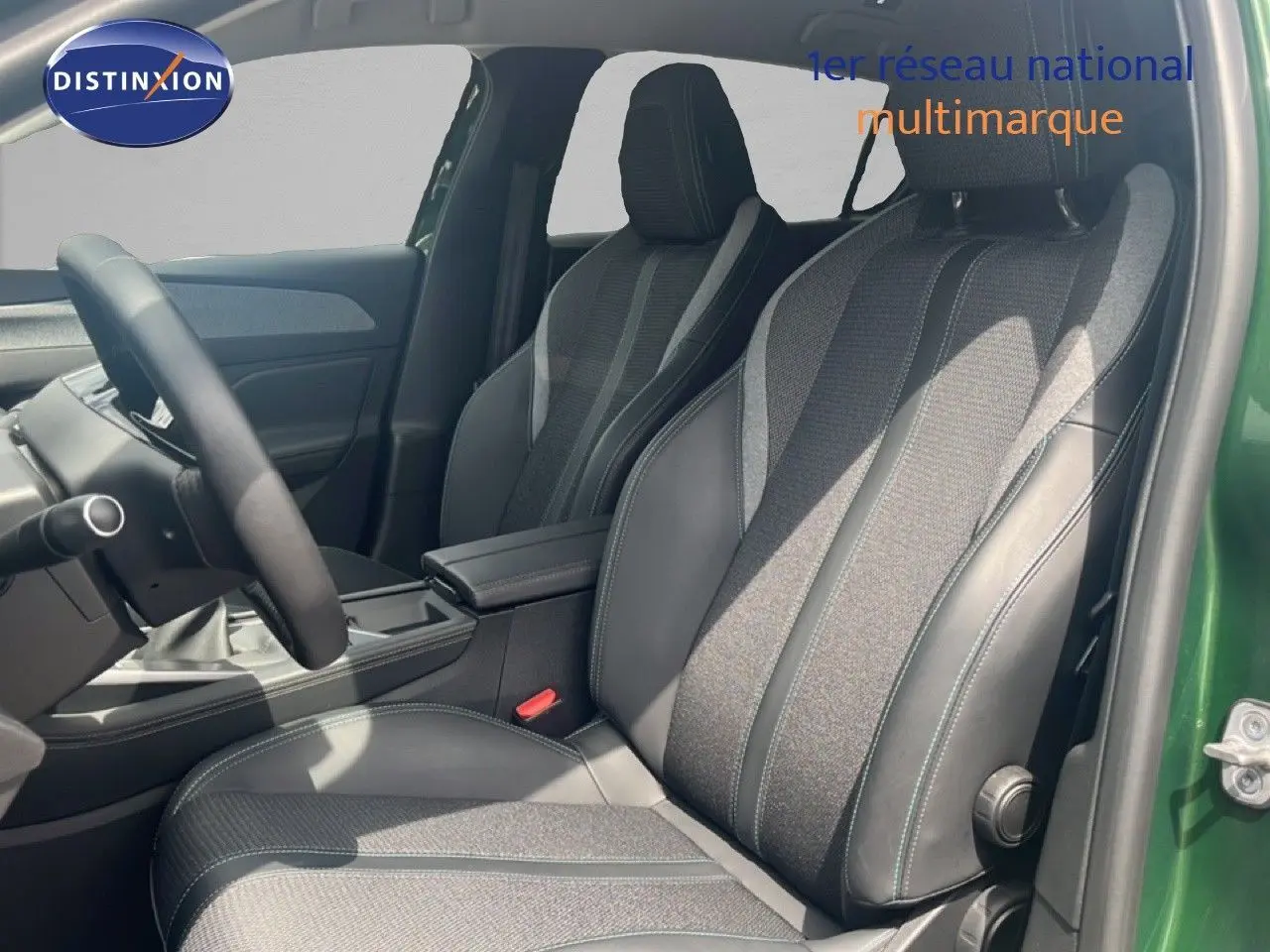 Vue intérieure côté conducteur de la Peugeot 308 2024 vert olivine, sièges en tissu et cuir gris noir, volant multifonction.