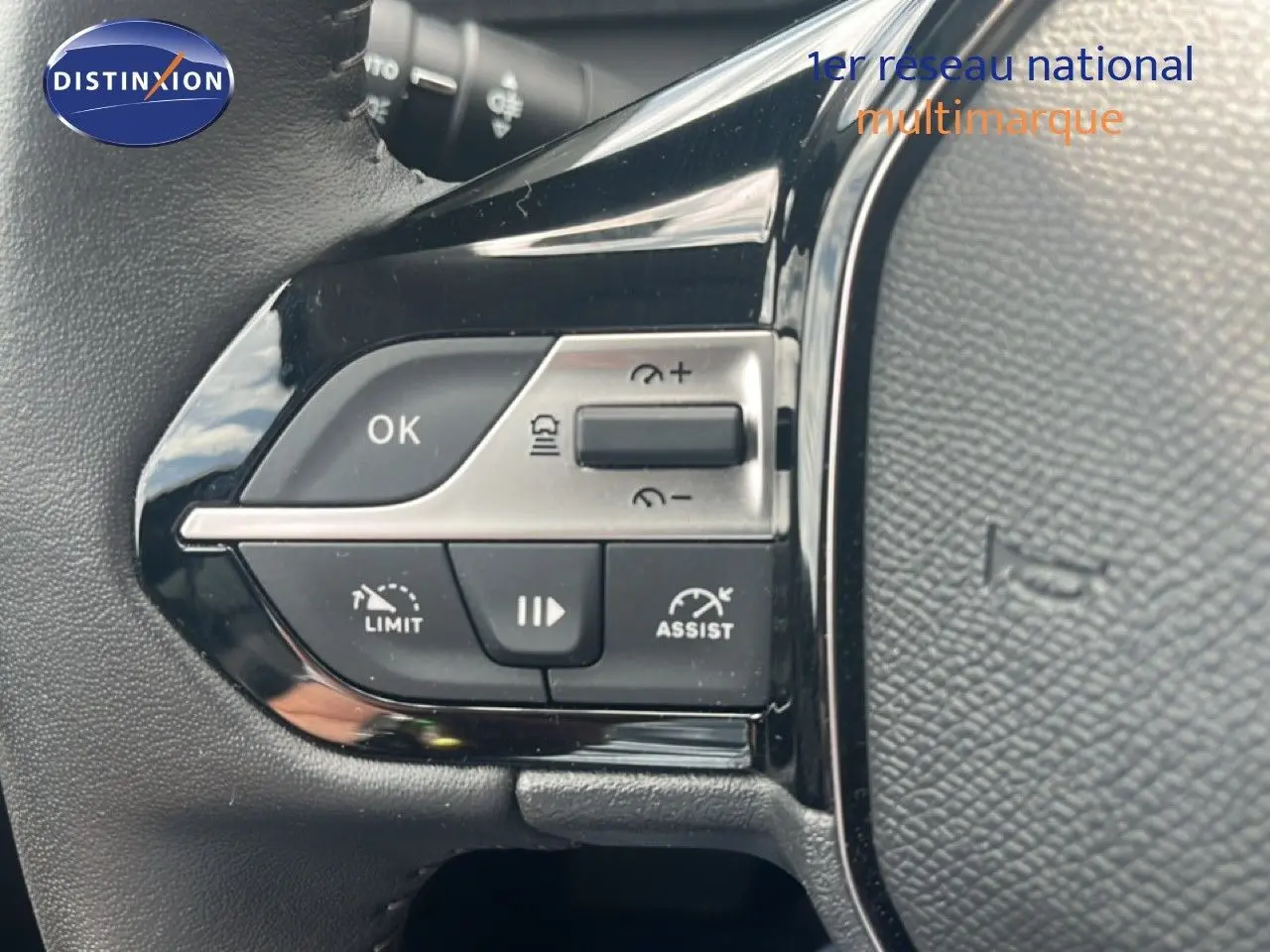 Gros plan sur les commandes de régulateur et limiteur de vitesse au volant d’une Peugeot 308 vert olivine métal.