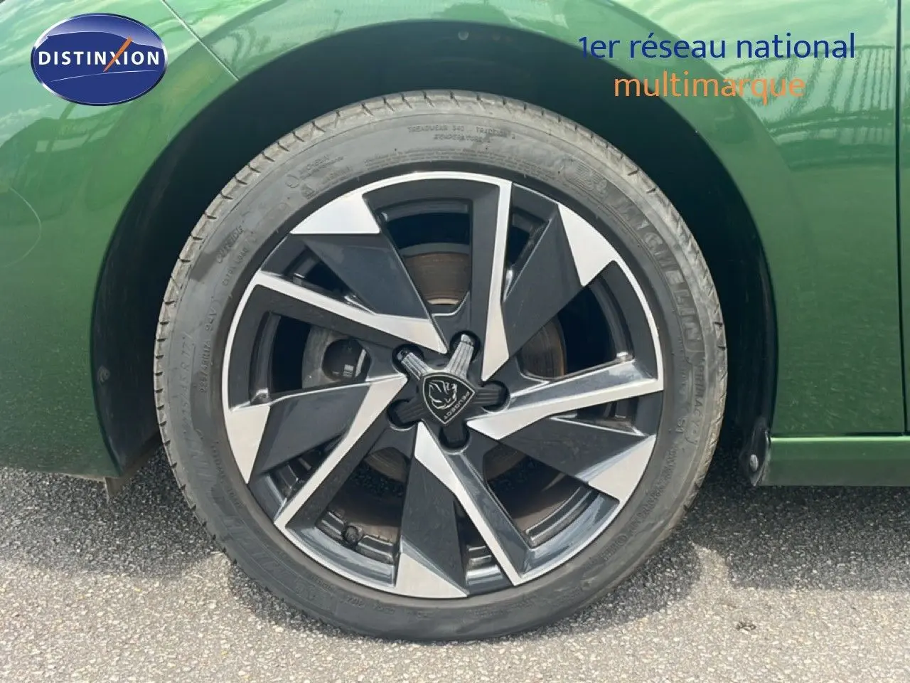 Gros plan sur la roue avant gauche de la Peugeot 308 2024 vert olivine métal avec jante alliage bicolore distinctive.