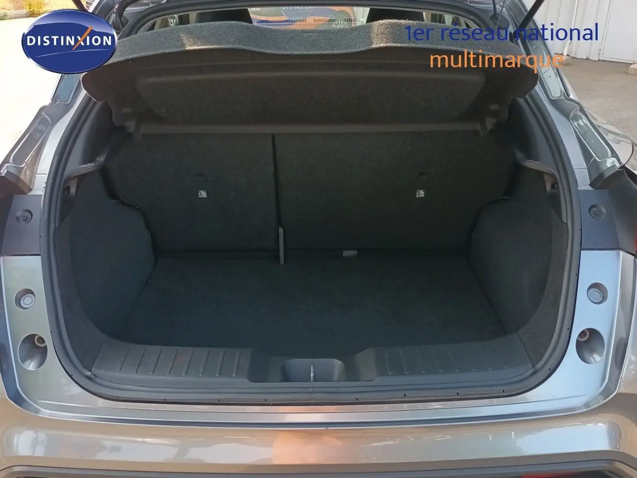 Coffre ouvert vu de l'arrière d'un Nissan Juke 2025 gris squale métal, montrant l'espace de chargement vide.
