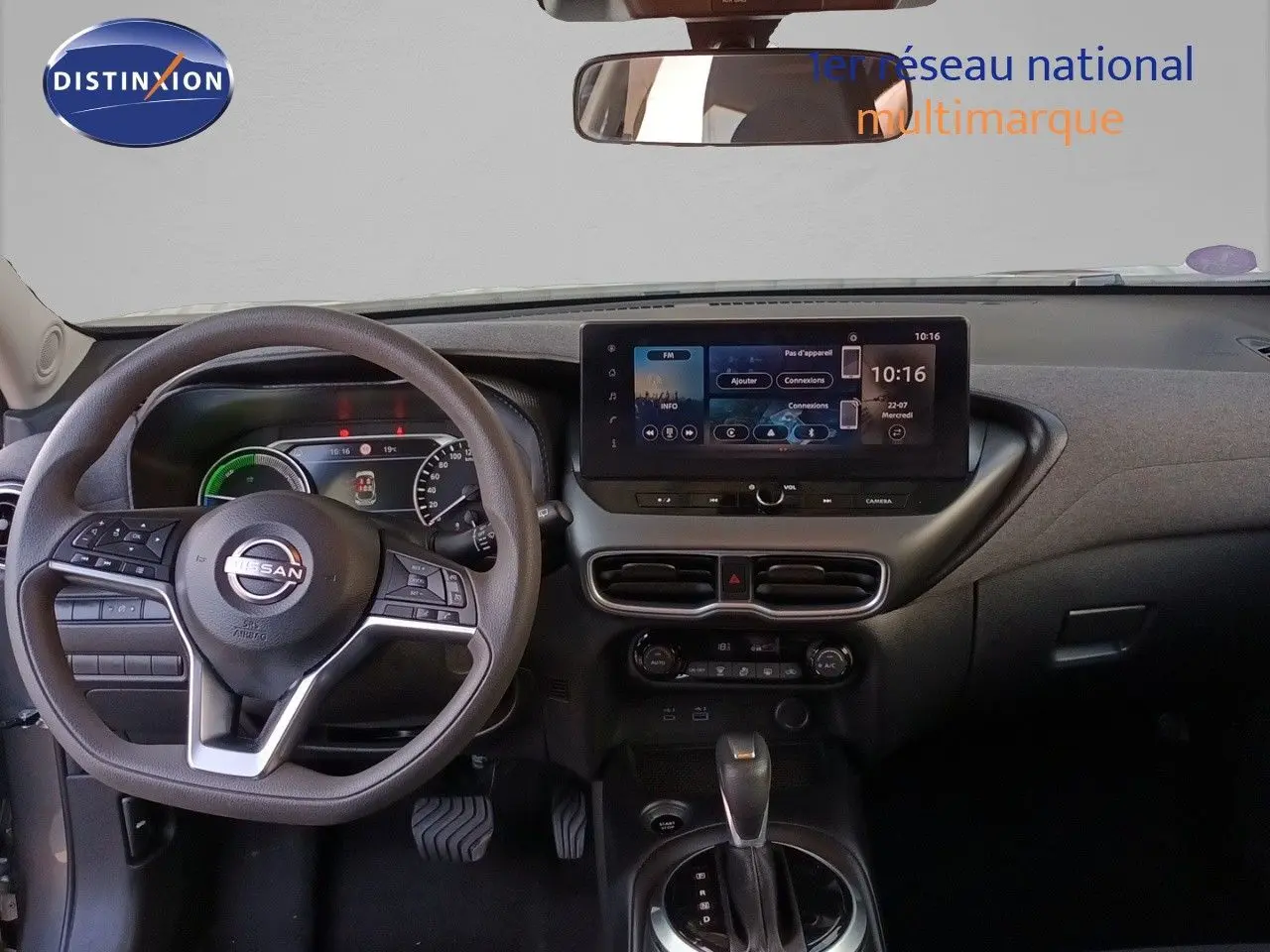 Vue intérieure frontale du tableau de bord du Nissan Juke Hybrid 2025 avec écran tactile et volant multifonction noir.