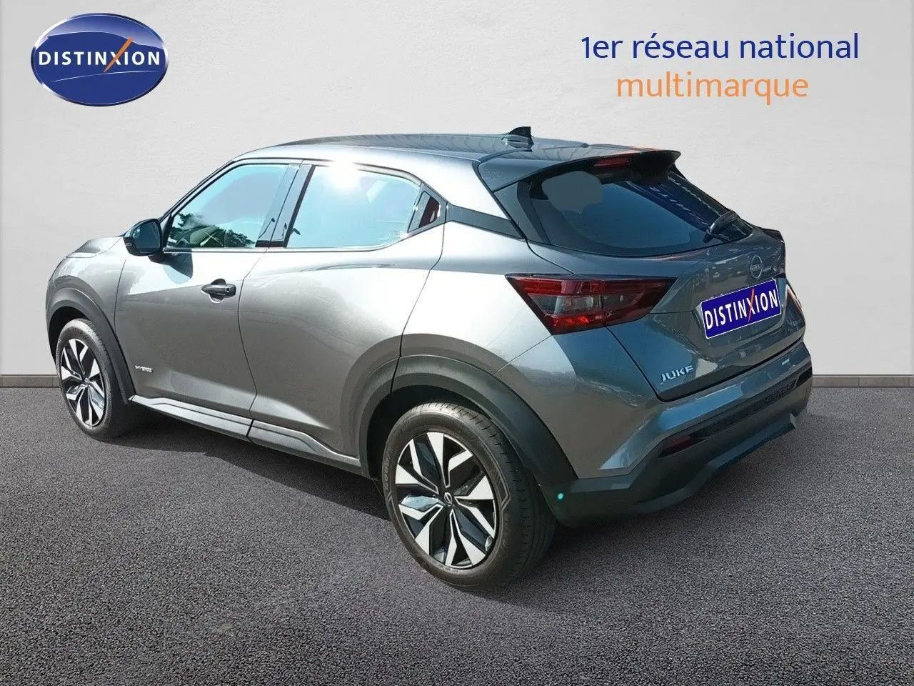Nissan Juke Hybrid gris squale métal, vue 3/4 arrière droit, avec jantes alliage et vitres teintées.