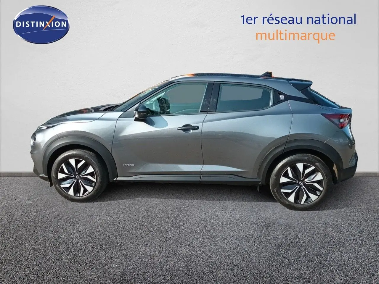 Profil droit du Nissan Juke hybride 2025 gris squale métal avec jantes noires et détails noirs contrastants.