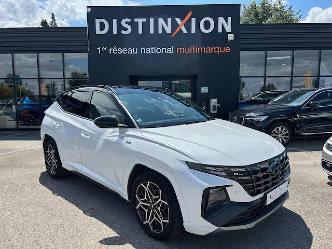 Hyundai Tucson IV blanc polaire toit noir vu en 3/4 avant droit avec calandre N-Line et jantes distinctives.