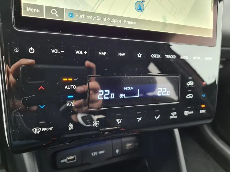 Gros plan sur la console centrale du Hyundai Tucson blanc polaire, affichant la climatisation automatique à 22°C.