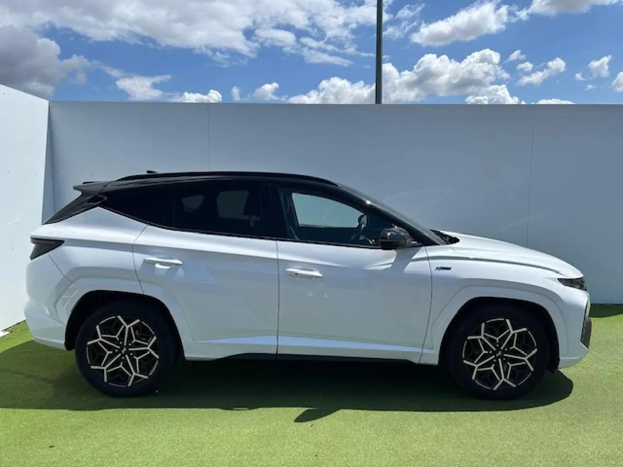 Vue latérale droite du Hyundai Tucson blanc polaire avec toit noir et jantes au design géométrique.