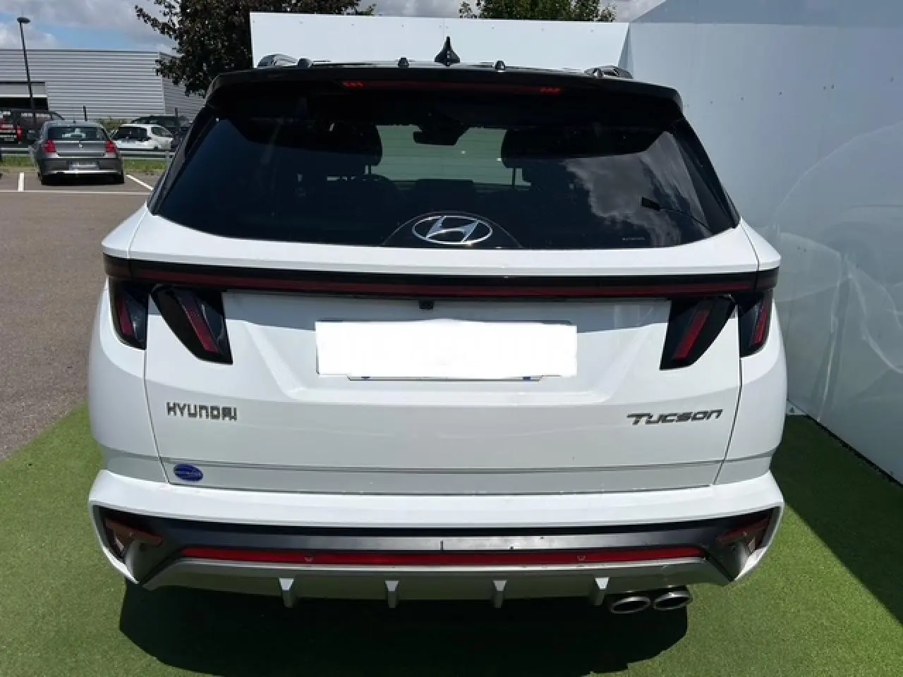 Vue arrière d'un Hyundai Tucson blanc polaire avec toit noir, feux arrière LED et double sortie d'échappement chromée.