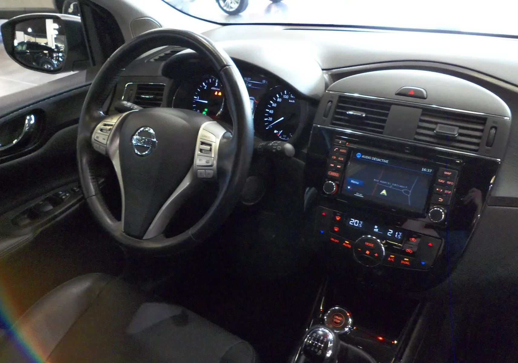 Vue intérieure côté conducteur du Nissan Pulsar gris glacier 2019, avec tableau de bord et écran tactile de navigation.