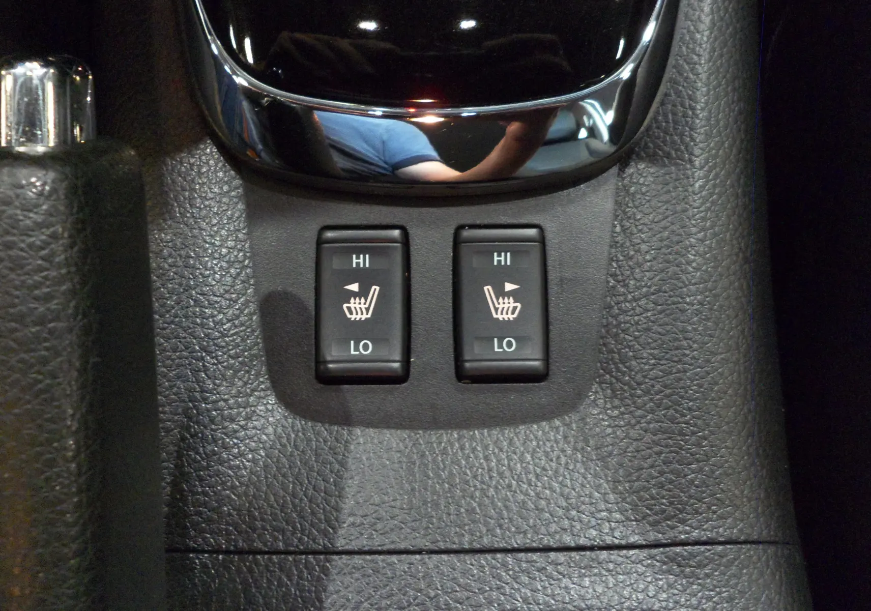 Gros plan sur les boutons de chauffage des sièges avant dans l'habitacle noir du Nissan Pulsar gris Glacier 2019.