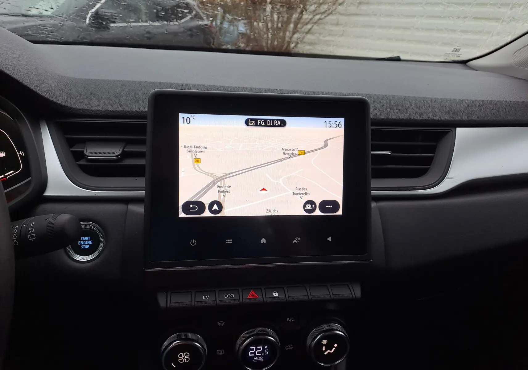 Vue intérieure centrée sur l’écran tactile du tableau de bord du Renault Captur gris, avec commandes climatisation et bouton start visible.