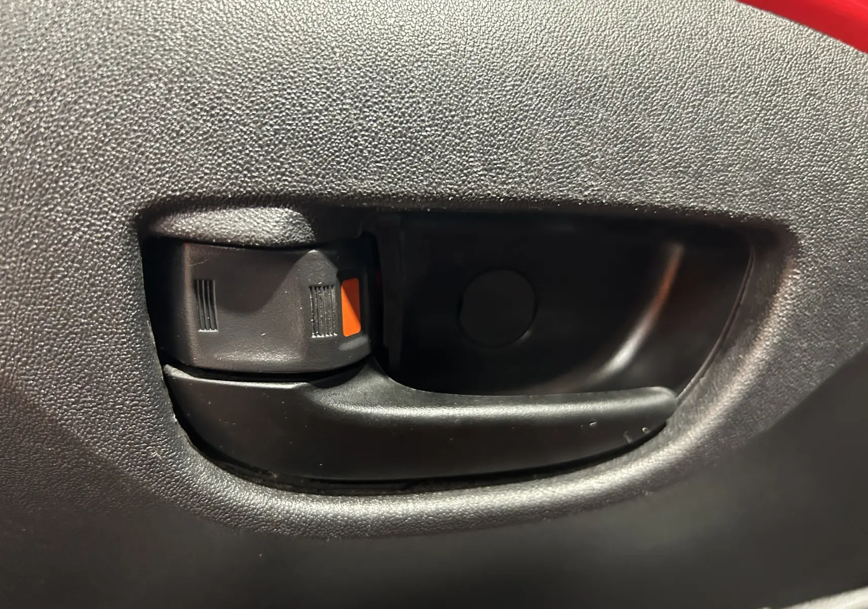 Poignée intérieure de porte noire sur fond de panneau de porte rouge d'une Citroën C1 Airscape 2019.