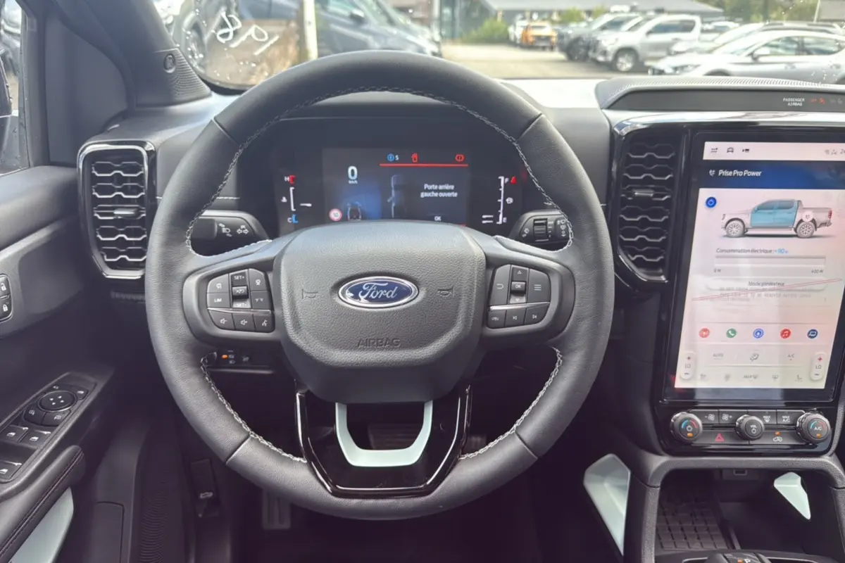 Vue intérieure centrée sur le volant du Ford Ranger 2025 noir agate avec écran tactile et commandes au volant.