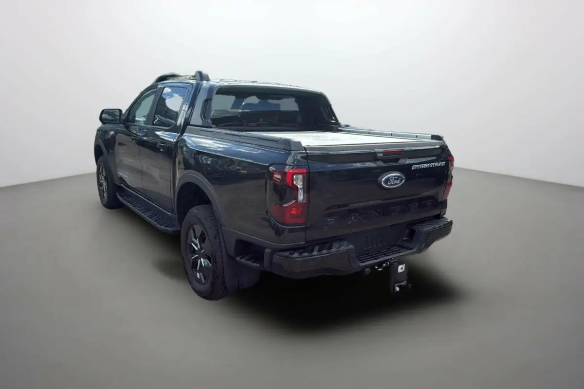 Ford Ranger 2025 noir agate vu en 3/4 arrière droit avec benne couverte et logo Stormtrak visible