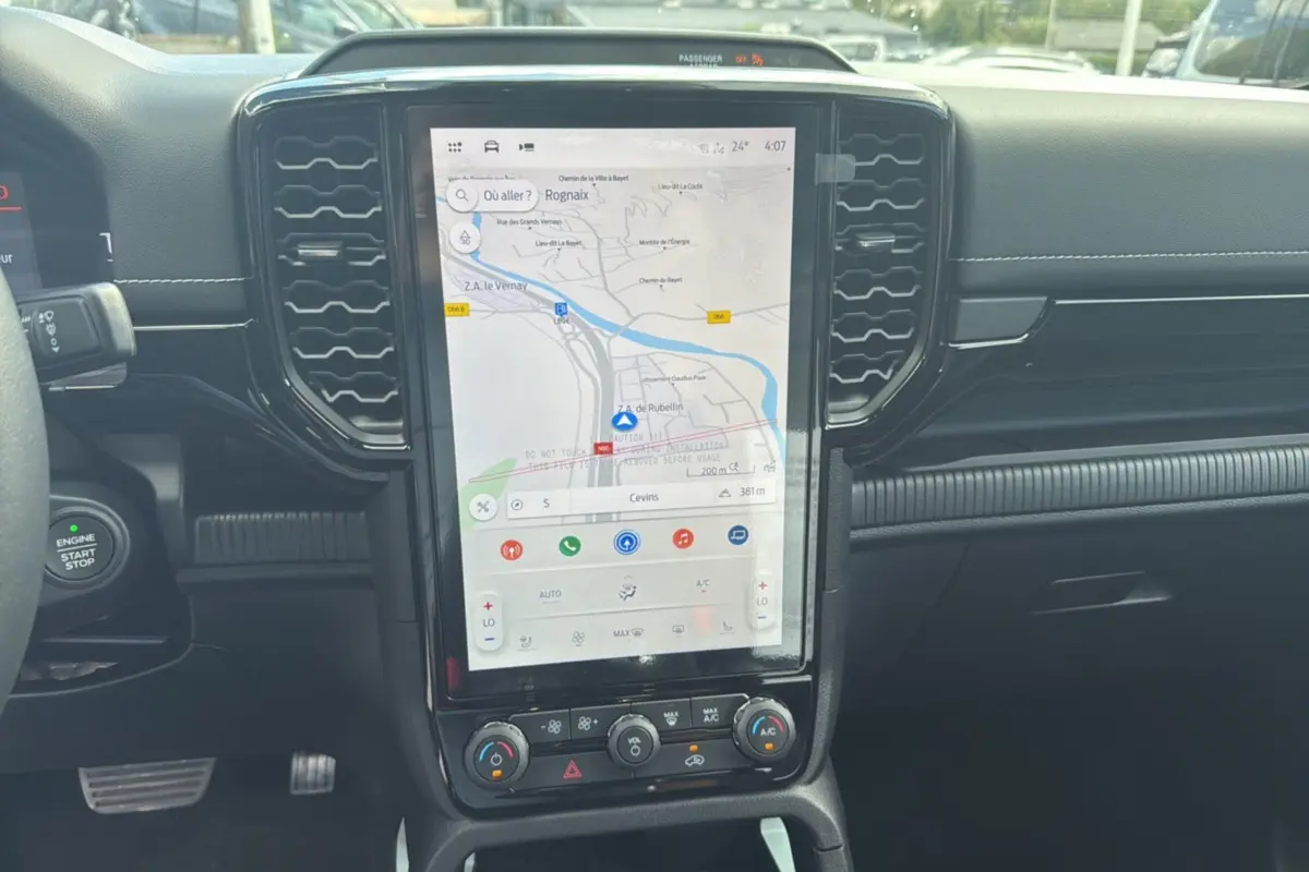Vue rapprochée de l'écran tactile central et tableau de bord noir du Ford Ranger 2025 hybride, avec navigation affichée.