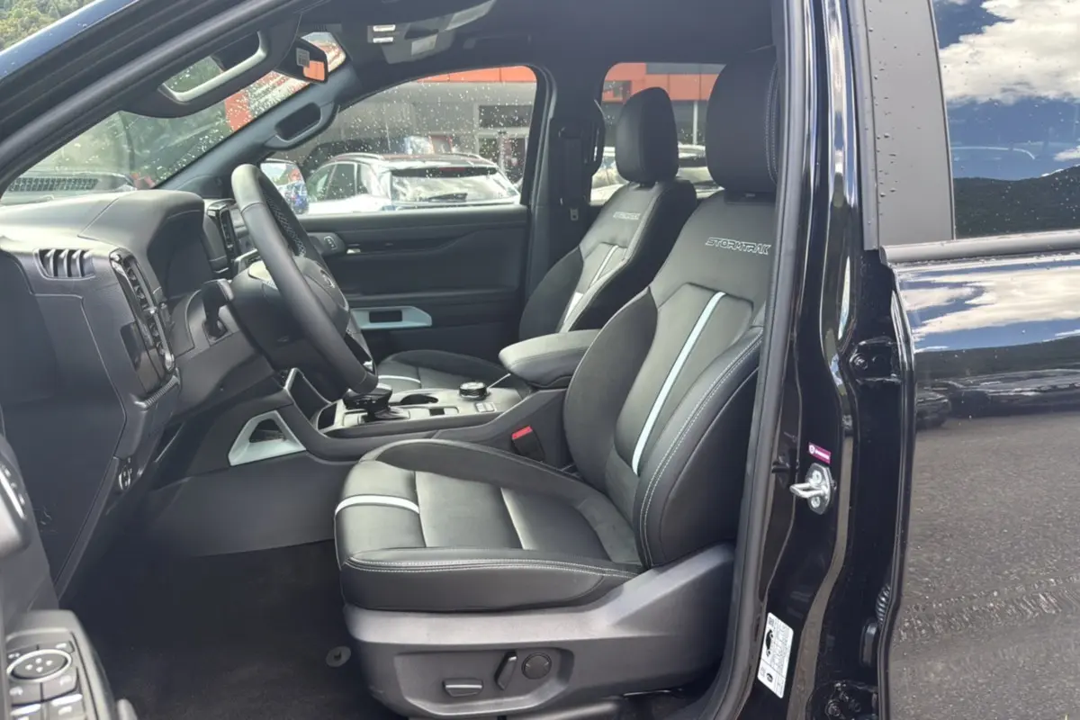 Intérieur du Ford Ranger 2025 noir agate, vue côté conducteur ouverte, sièges Stormtrak avec surpiqûres blanches visibles.