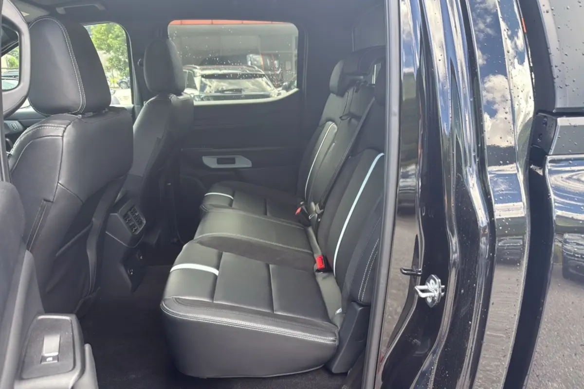 Vue intérieure côté gauche sur les sièges arrière en cuir noir du Ford Ranger 2025 noir agate avec détails blancs.