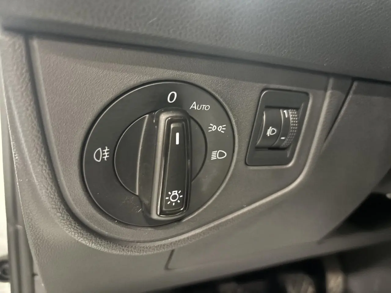 Gros plan sur le sélecteur de feux noir dans l'habitacle du Volkswagen Taigo blanc, côté conducteur.