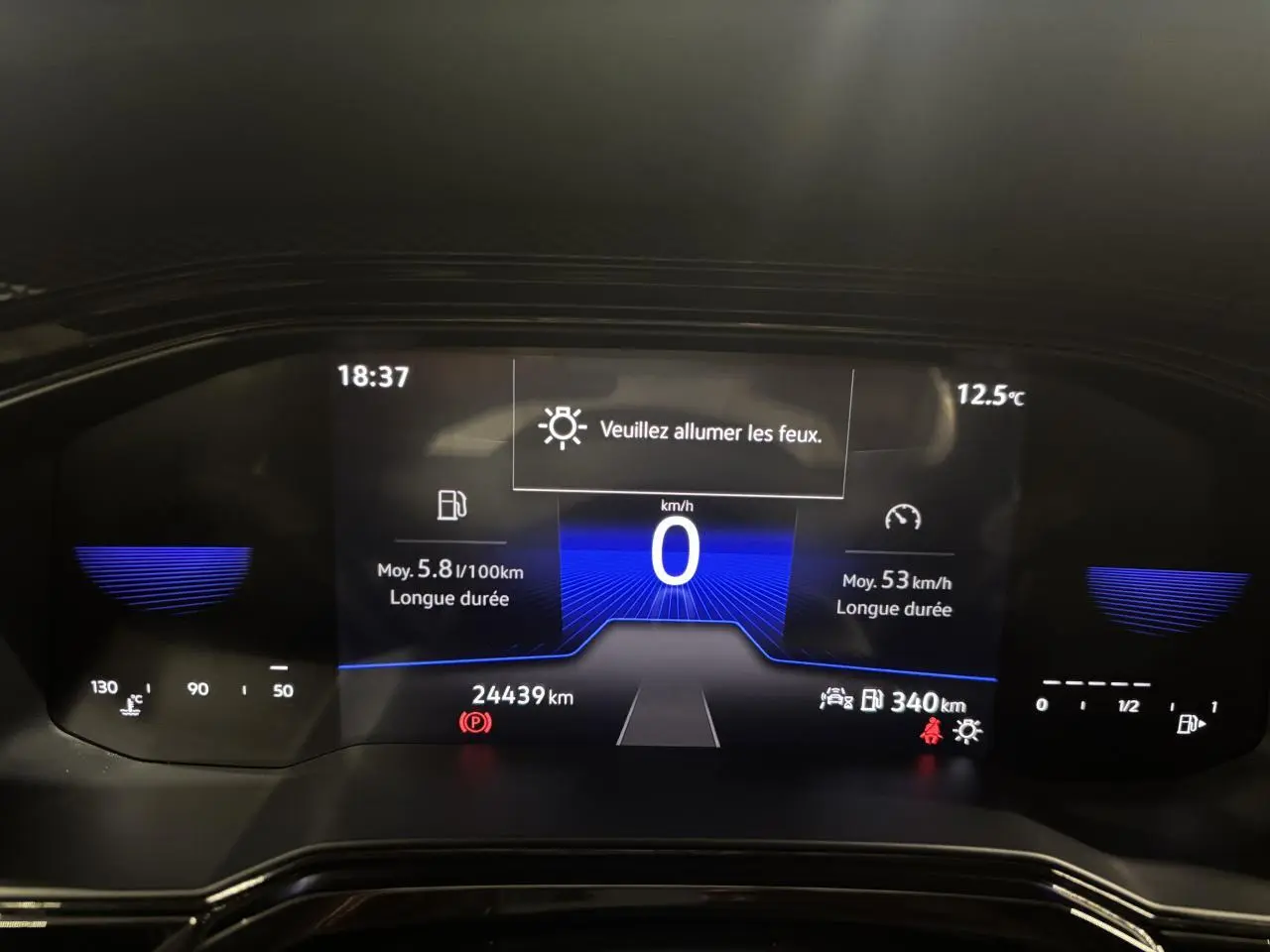 Tableau de bord numérique du Volkswagen Taigo 2023 affichant 0 km/h et un message "Veuillez allumer les feux".