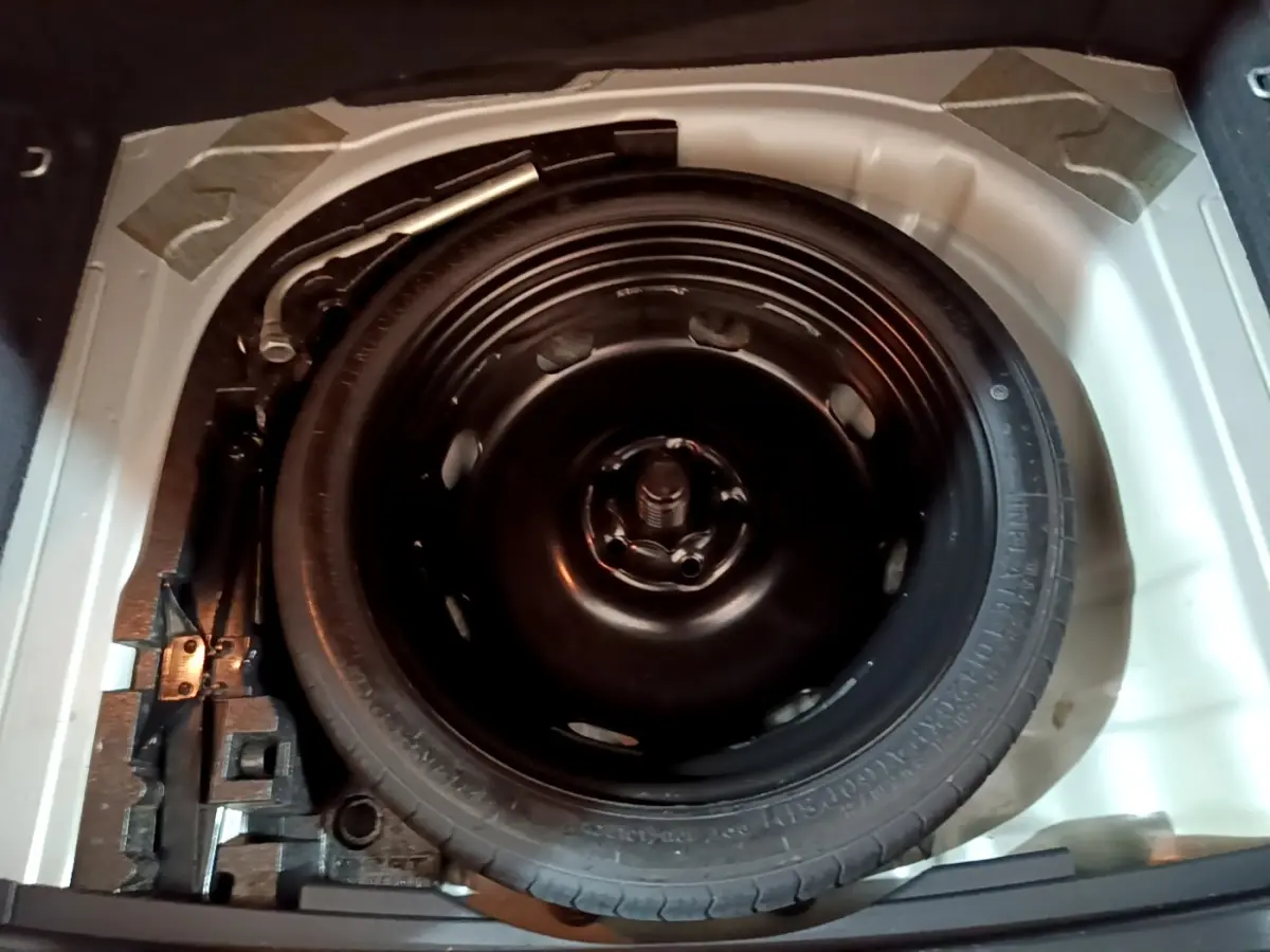 Vue plongeante sur la roue de secours galette noire dans le coffre du SEAT Ateca gris clair 2022.