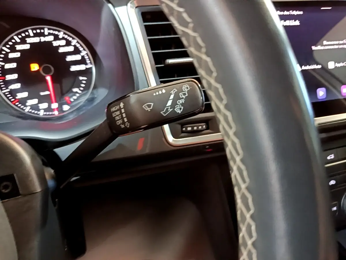 Vue rapprochée du commodo d’essuie-glace à gauche du volant cuir gris du SEAT Ateca 2022, tableau de bord et écran tactile visibles.