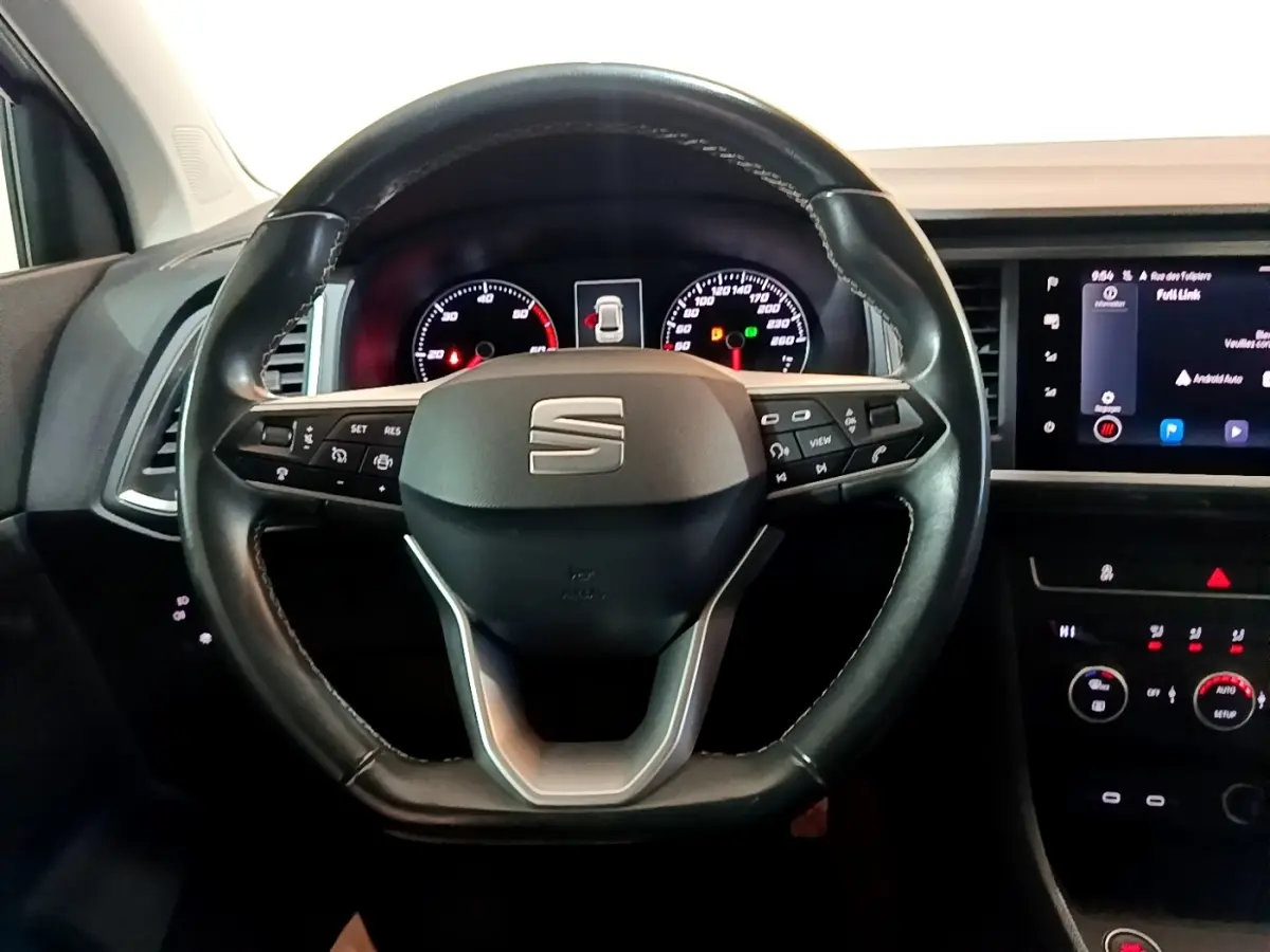 Vue centrée sur le volant en cuir noir du SEAT Ateca 2022 avec tableau de bord et écran tactile à droite.