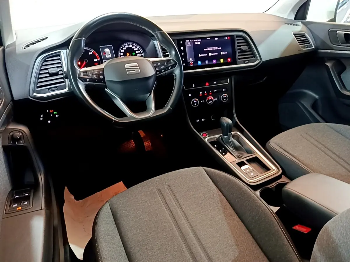 Vue intérieure avant du SEAT Ateca 2022, volant cuir alu multifonctions et écran tactile central allumé.