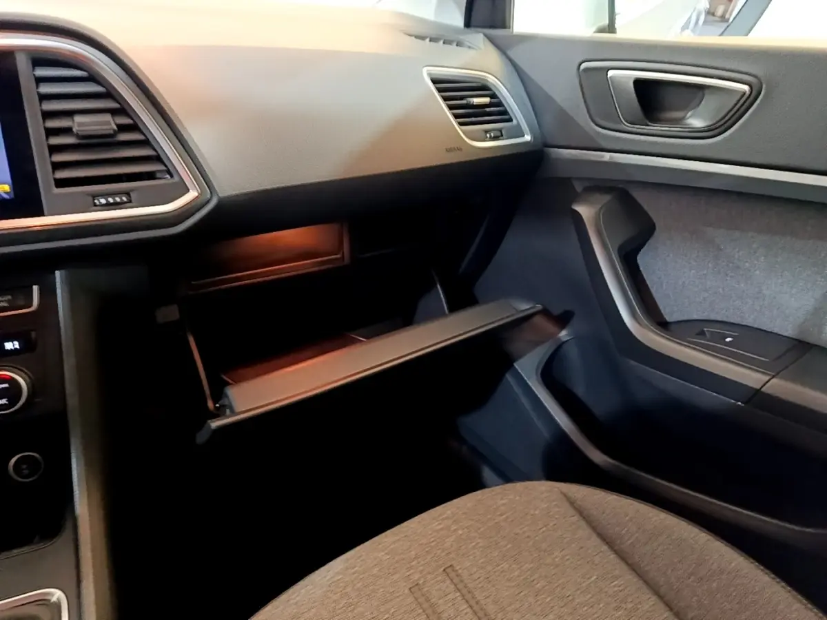 Vue intérieure côté passager du tableau de bord gris clair et boîte à gants ouverte du SEAT Ateca 2022.