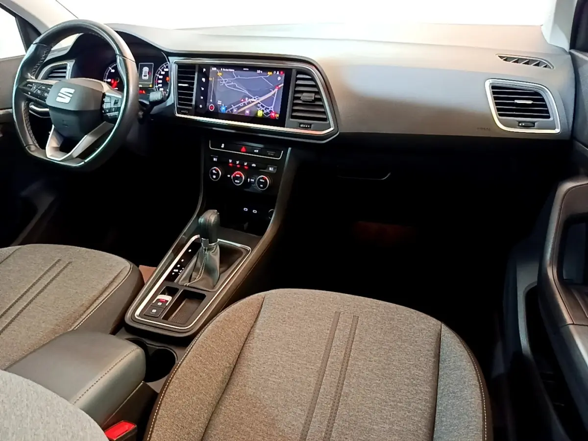 Vue intérieure avant du SEAT Ateca 2022, tableau de bord noir avec écran tactile de navigation et sièges tissu gris.