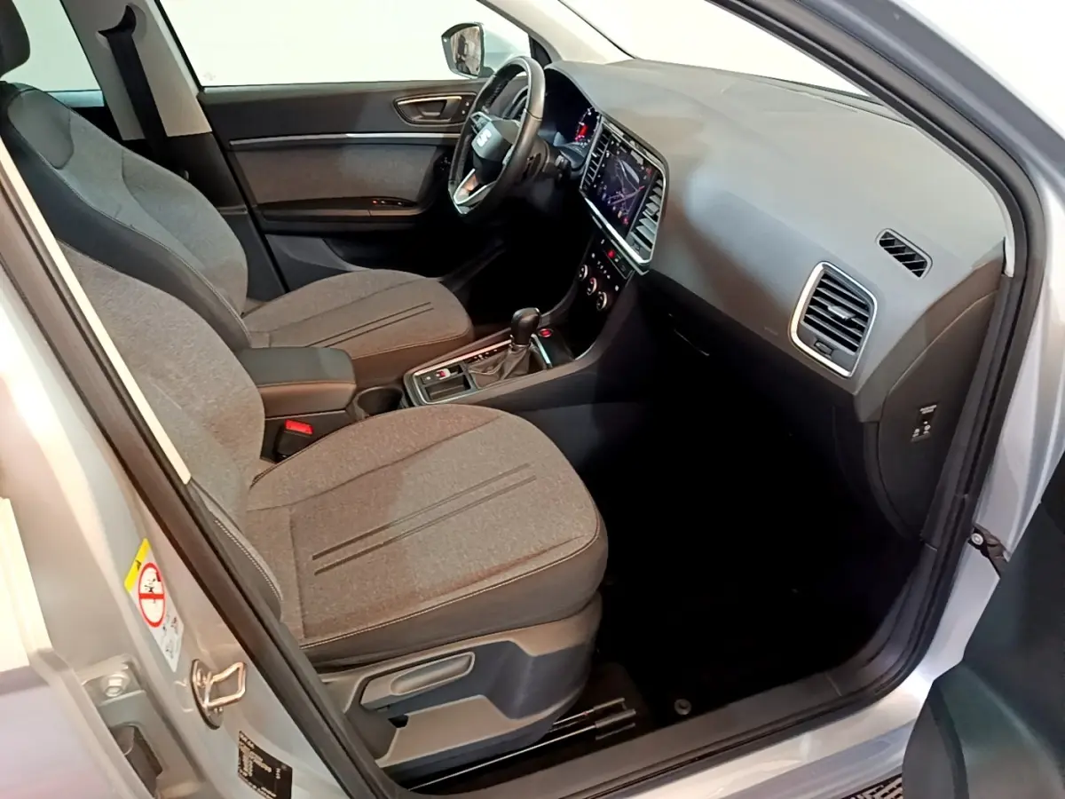 Vue intérieure côté conducteur du SEAT Ateca gris clair 2022, avec tableau de bord moderne et sièges tissu gris.
