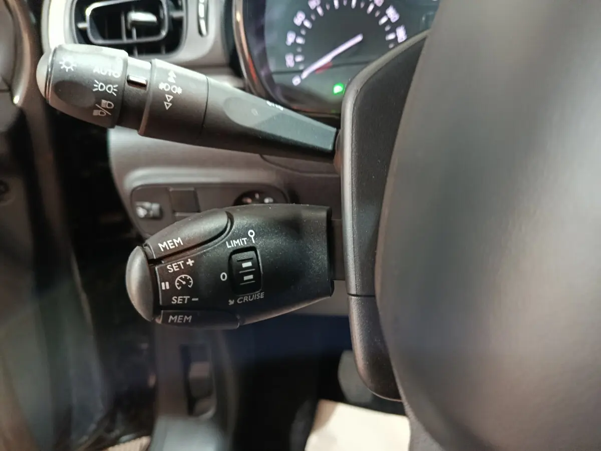 Gros plan sur la commande de régulateur de vitesse à gauche du volant dans l’habitacle d’une Citroën C3 gris foncé 2024.