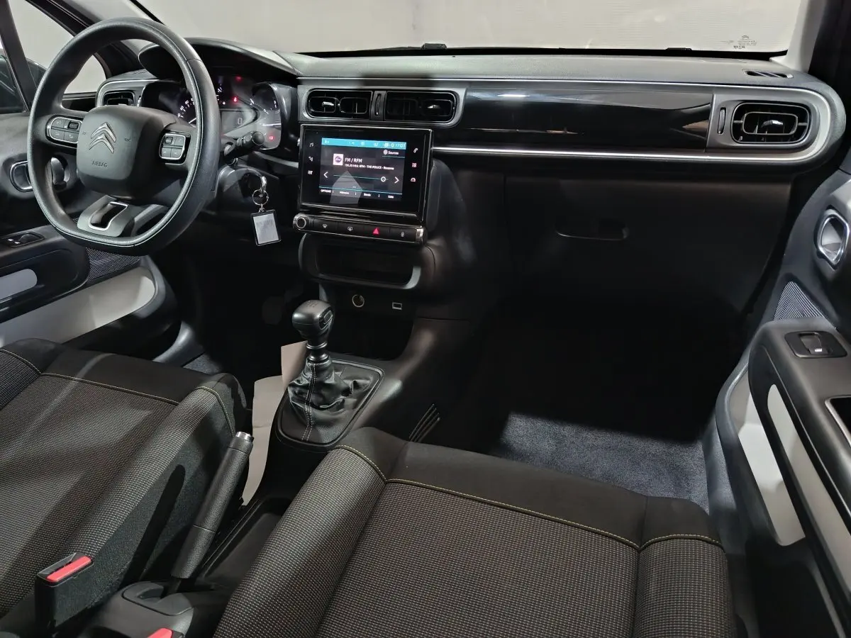 Intérieur avant droit de la Citroën C3 2024 gris foncé, volant multifonctions, écran tactile central et boîte manuelle.