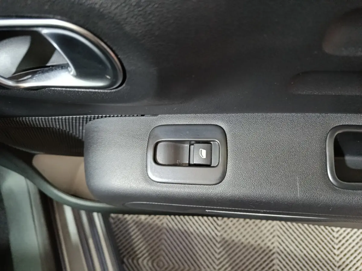 Gros plan sur le bouton de commande de la vitre électrique côté conducteur d’une Citroën C3 gris foncé 2024.