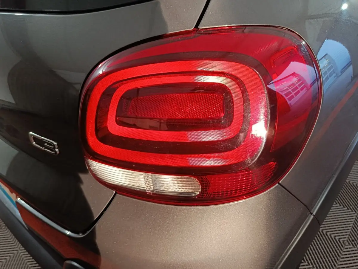 Gros plan sur le feu arrière droit rouge de la Citroën C3 gris foncé, avec logo C3 visible sur la carrosserie.