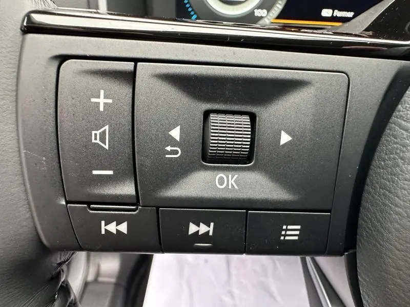 Gros plan sur les commandes au volant du Nissan Qashqai Hybrid e-POWER 2025, boutons noirs avec symboles blancs.