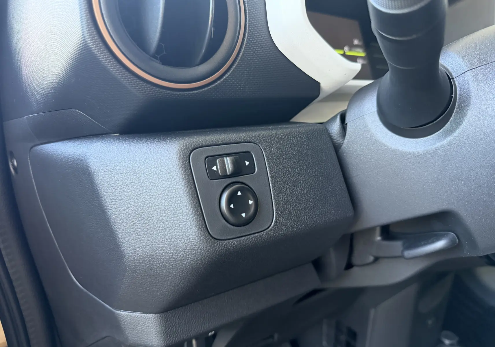 Gros plan sur les commandes de réglage des rétroviseurs côté gauche du tableau de bord du Dacia Spring 65 Extreme beige Safari.