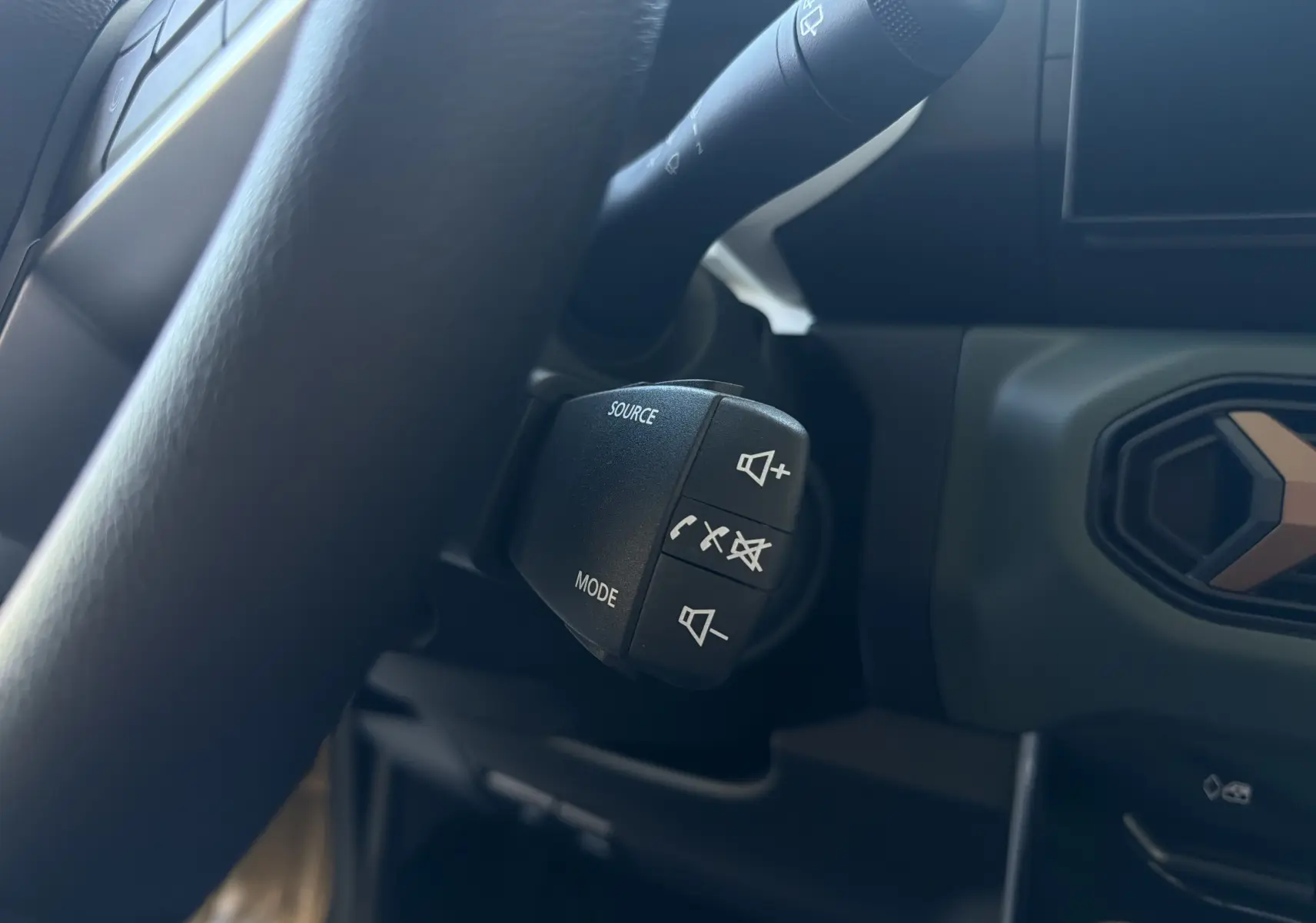 Gros plan sur les commandes au volant du Dacia Spring 65 Extreme 2026, intérieur noir avec détails beige safari visibles.